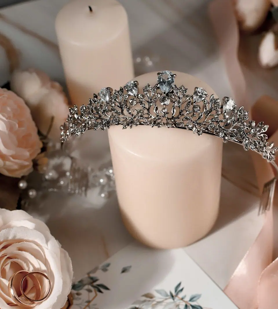Tiara plateada sobre una vela entre rosas